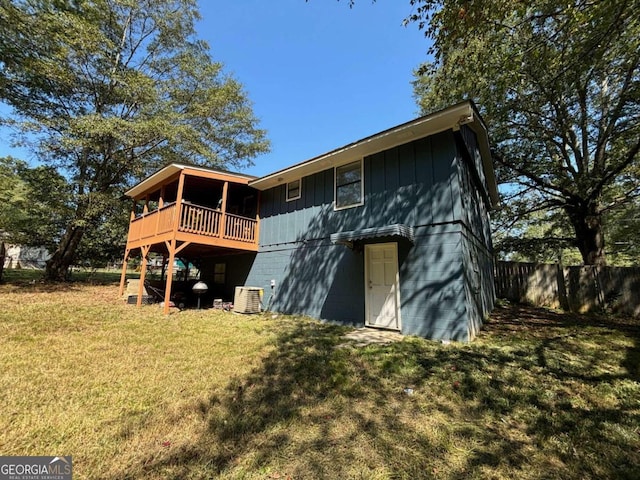 rear view of property featuring central AC, a lawn, a wooden deck, and fence