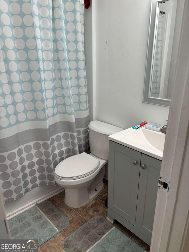 bathroom with toilet, curtained shower, tile patterned flooring, and vanity