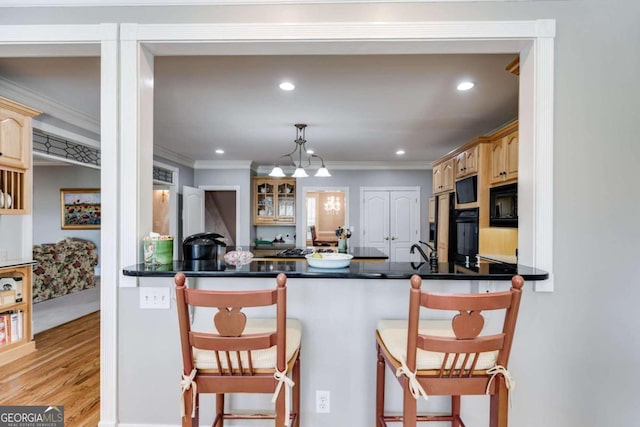 kitchen featuring black appliances, kitchen peninsula, pendant lighting, and a kitchen bar