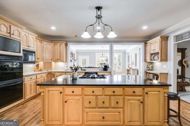 kitchen with hanging light fixtures, light hardwood / wood-style floors, black appliances, a center island, and an inviting chandelier