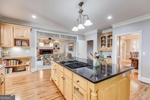 kitchen featuring light brown cabinets, ornamental molding, black gas cooktop, light hardwood / wood-style flooring, and a fireplace