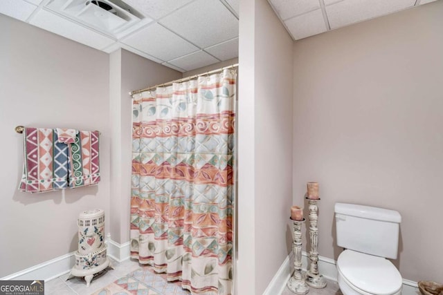 bathroom with walk in shower, a drop ceiling, toilet, and tile patterned floors