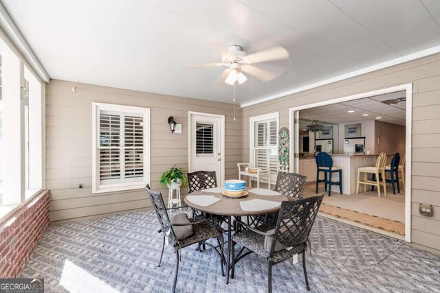 dining room featuring carpet flooring, wooden walls, and ceiling fan