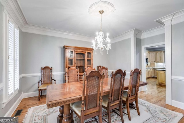 dining space featuring ornamental molding, light hardwood / wood-style floors, plenty of natural light, and an inviting chandelier