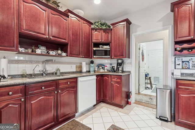 kitchen with backsplash, white dishwasher, light tile patterned floors, and sink