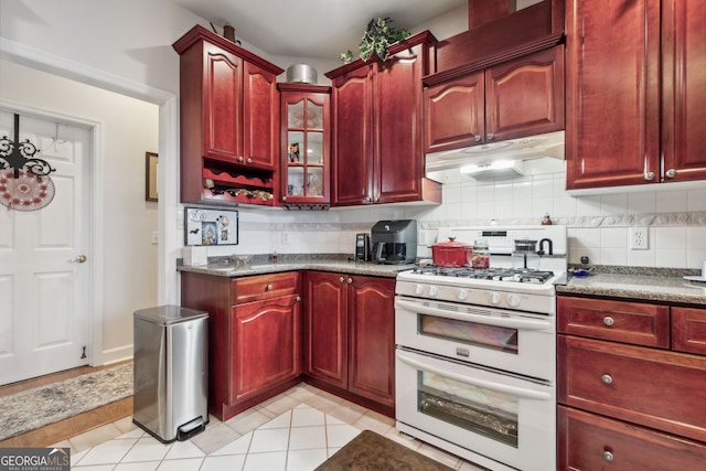 kitchen featuring light tile patterned flooring, white gas range oven, and tasteful backsplash