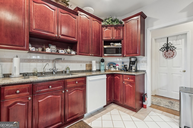 kitchen with sink, dishwasher, dark stone countertops, light wood-type flooring, and decorative backsplash