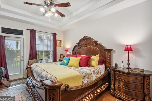 bedroom featuring wood-type flooring, a tray ceiling, ceiling fan, and access to exterior