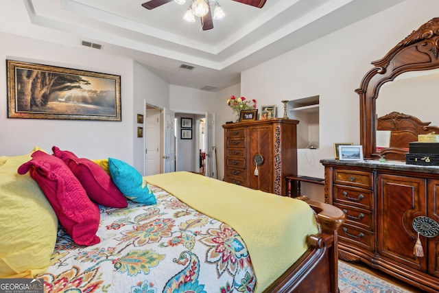 bedroom with ceiling fan and a raised ceiling