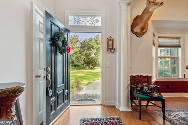 entrance foyer with decorative columns and light hardwood / wood-style floors