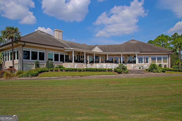 rear view of property with a lawn and a sunroom