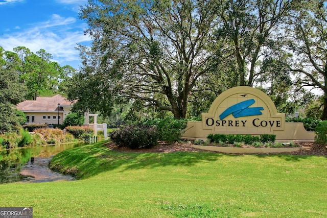 community / neighborhood sign with a lawn and a water view