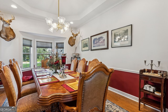 dining room with hardwood / wood-style flooring, a tray ceiling, crown molding, and a notable chandelier