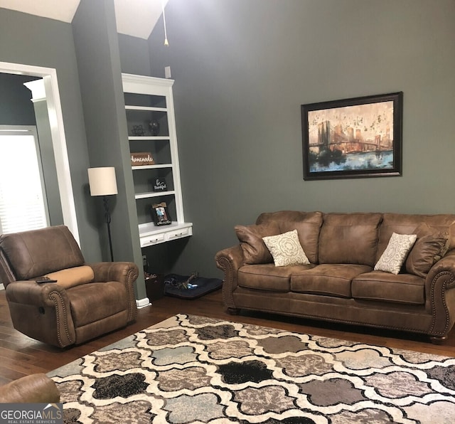 living room with built in shelves and dark wood-type flooring