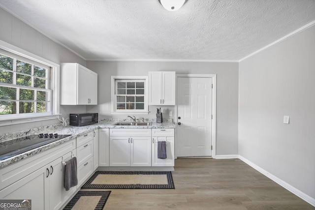 kitchen featuring white cabinetry, light stone countertops, wood-type flooring, and black appliances