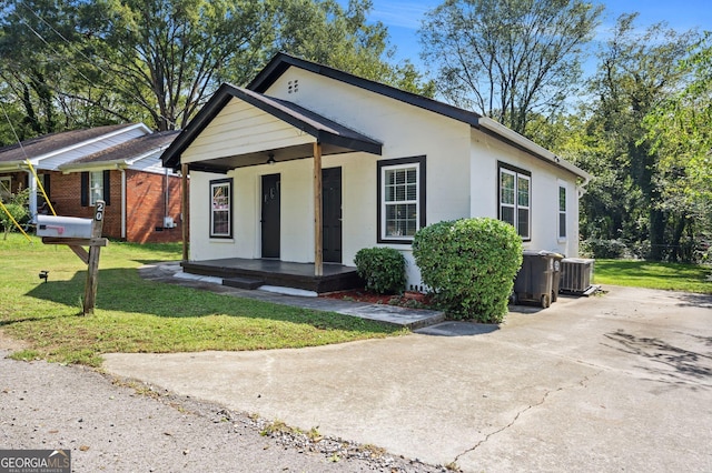 ranch-style house featuring cooling unit, a porch, and a front lawn