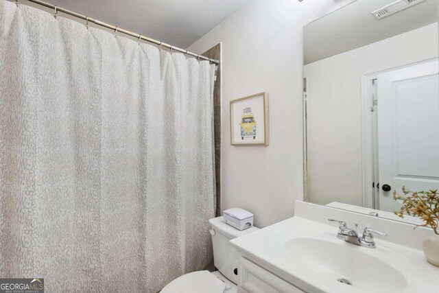 bathroom featuring walk in shower, vanity, and toilet