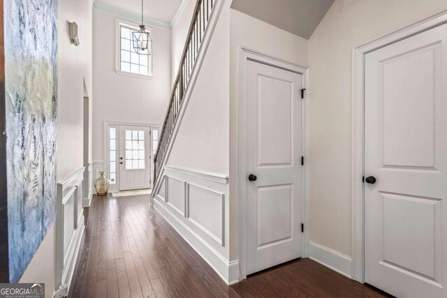 entryway featuring a healthy amount of sunlight, ornamental molding, an inviting chandelier, and dark wood-type flooring