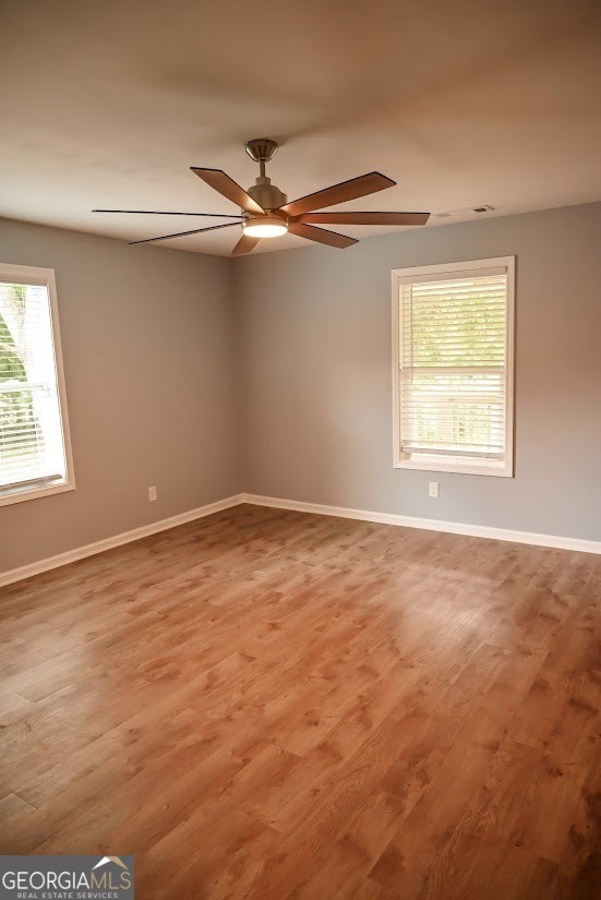 unfurnished room featuring ceiling fan, hardwood / wood-style flooring, and a wealth of natural light