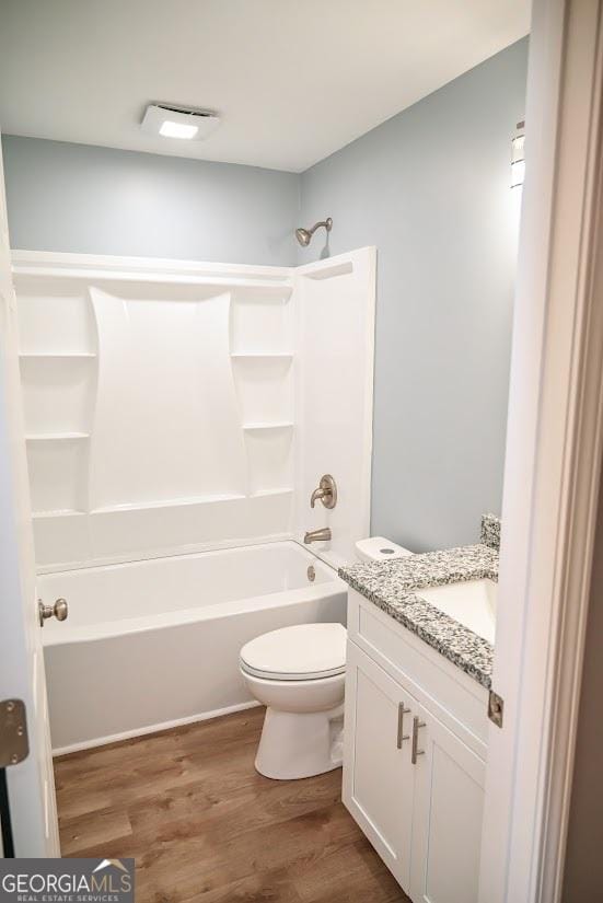 full bathroom with vanity, toilet, tub / shower combination, visible vents, and wood finished floors