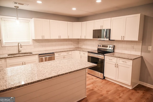 kitchen featuring sink, stainless steel appliances, and light stone counters