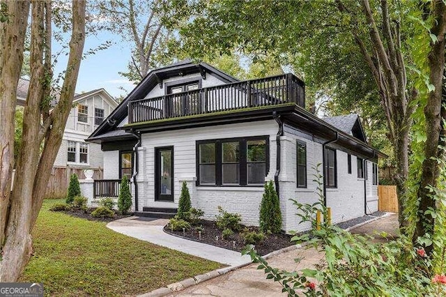 view of front of house with a balcony and a front lawn