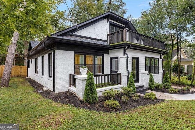 view of side of home with a lawn and a balcony