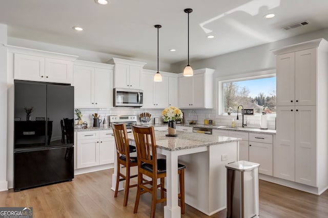 kitchen featuring a kitchen island, appliances with stainless steel finishes, and white cabinets