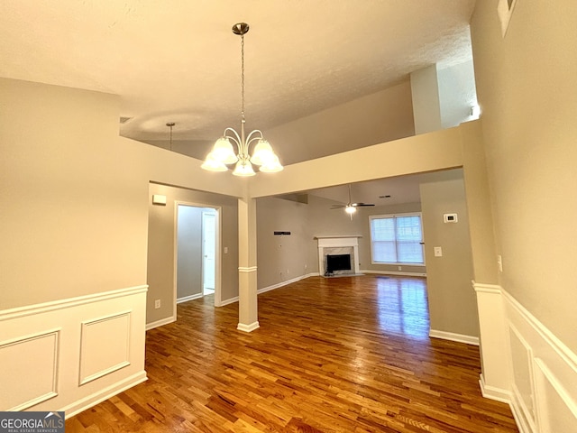 unfurnished living room with ceiling fan with notable chandelier, lofted ceiling, a textured ceiling, and hardwood / wood-style flooring