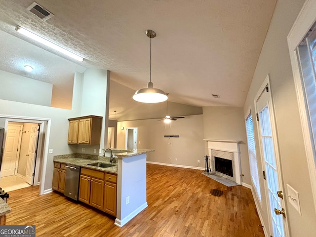 kitchen with light wood-type flooring, dishwasher, sink, a premium fireplace, and kitchen peninsula