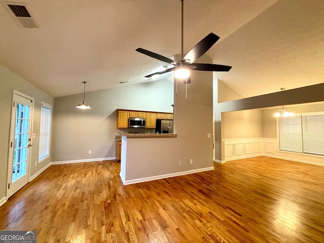 unfurnished living room with ceiling fan with notable chandelier, high vaulted ceiling, a textured ceiling, and hardwood / wood-style flooring