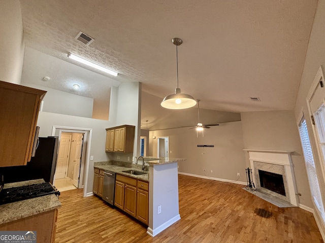 kitchen with sink, kitchen peninsula, stainless steel dishwasher, a textured ceiling, and light hardwood / wood-style floors