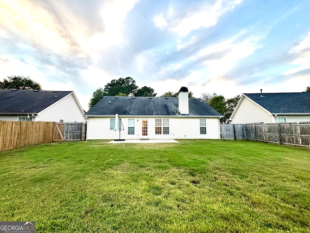 back of house featuring a lawn and a patio area