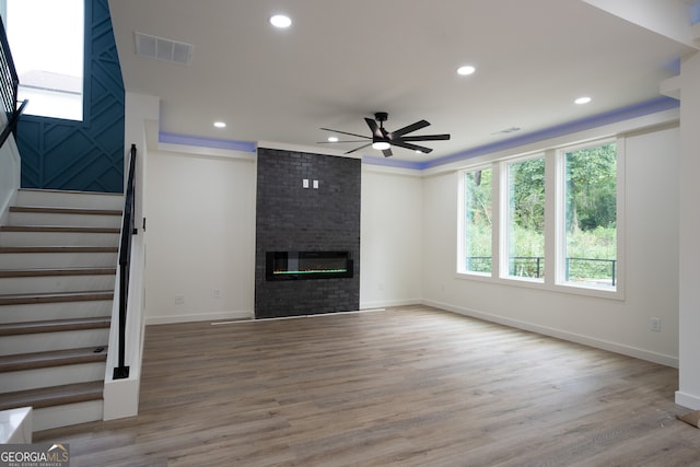 unfurnished living room featuring ceiling fan, hardwood / wood-style flooring, and a fireplace