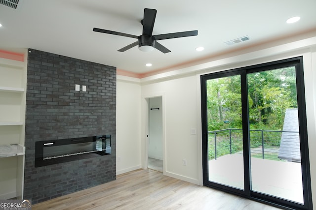 unfurnished living room featuring a brick fireplace, light wood-type flooring, and ceiling fan