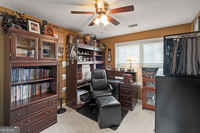 office featuring a textured ceiling, ceiling fan, and light colored carpet