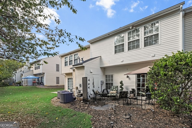 rear view of house with central AC unit, a lawn, and a patio area