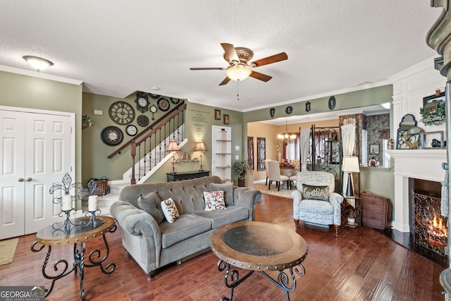 living room with ceiling fan with notable chandelier, a textured ceiling, dark hardwood / wood-style floors, and crown molding