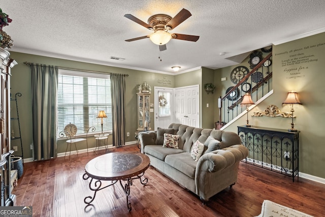 living room featuring ornamental molding, ceiling fan, dark hardwood / wood-style floors, and a textured ceiling