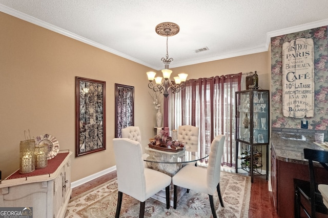 dining room featuring an inviting chandelier, a textured ceiling, hardwood / wood-style flooring, and crown molding