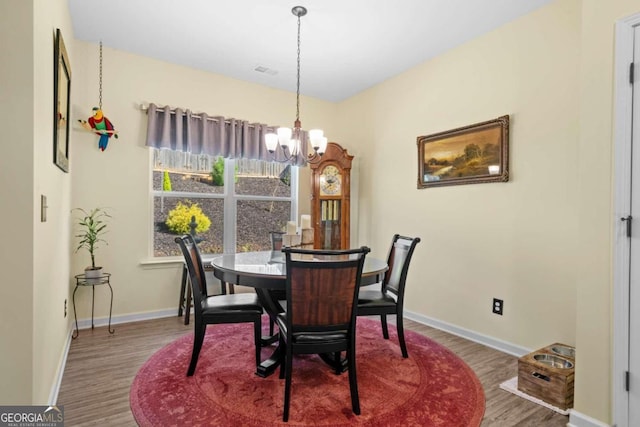 dining room with hardwood / wood-style floors and an inviting chandelier