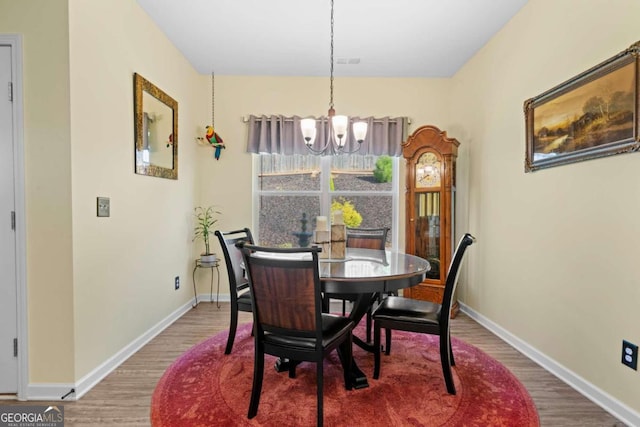 dining space featuring wood-type flooring and an inviting chandelier