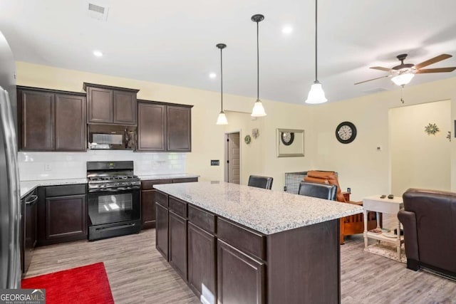 kitchen featuring pendant lighting, black appliances, a kitchen island, decorative backsplash, and dark brown cabinets