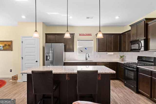 kitchen featuring a kitchen island, black appliances, a kitchen bar, and pendant lighting