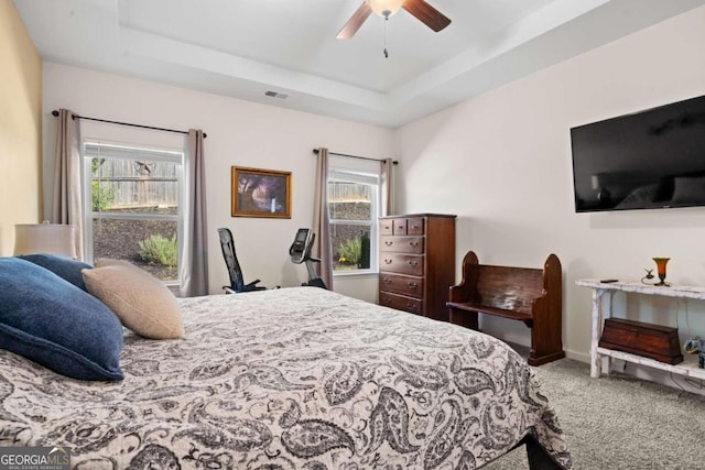 bedroom featuring ceiling fan, carpet flooring, and a tray ceiling