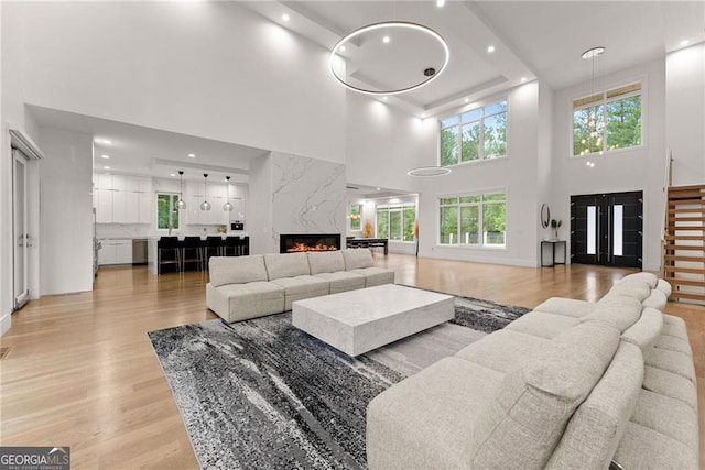 living room with a high ceiling, light hardwood / wood-style floors, and a fireplace