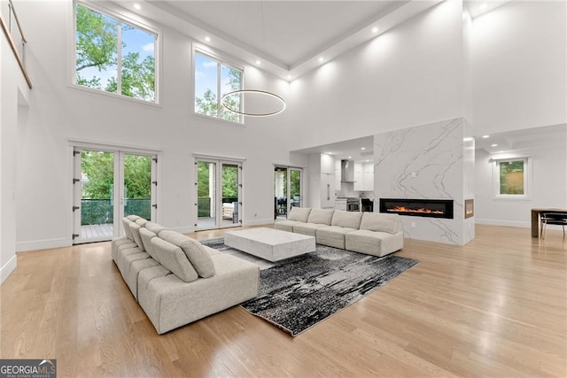 living room featuring light hardwood / wood-style floors, a fireplace, a high ceiling, and a wealth of natural light