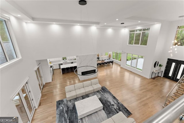 living room featuring light hardwood / wood-style flooring, a wealth of natural light, and a towering ceiling