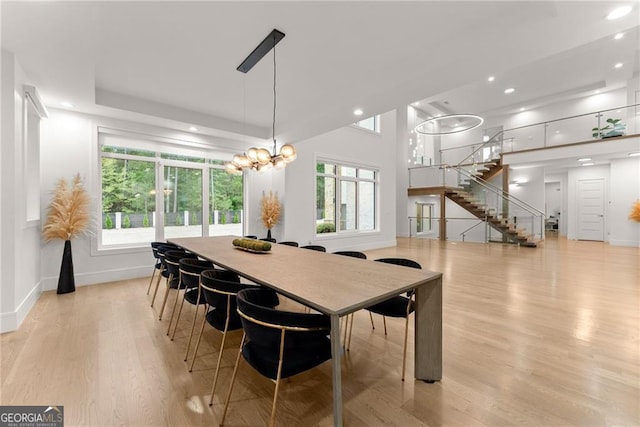 dining space with light hardwood / wood-style flooring, plenty of natural light, and a chandelier