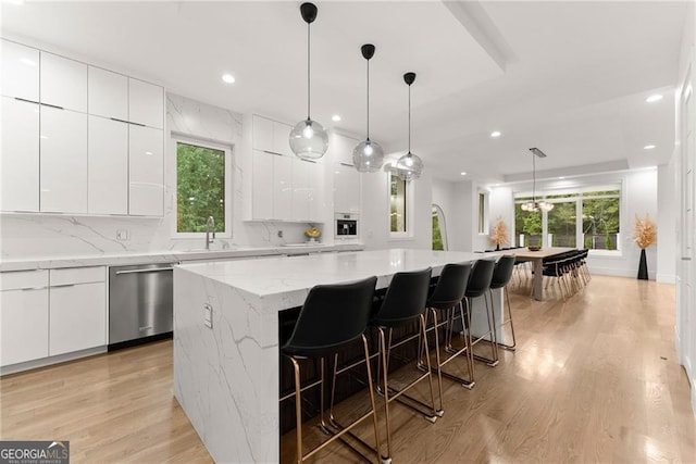 kitchen featuring dishwasher, light hardwood / wood-style floors, white cabinetry, and a kitchen island